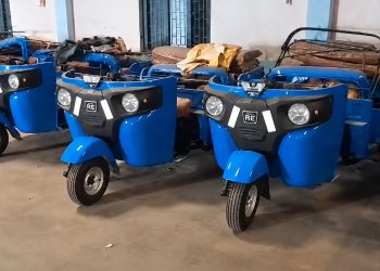 Multiple Bajaj RE 4S Compact auto rickshaws in blue lined up in Indian warehouse ready for shipment to Africa in SKD condition